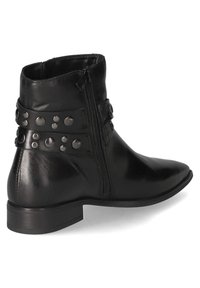 Botas de cuero negro hasta el tobillo con punta afilada, cremallera lateral y tachuelas decorativas en dos correas alrededor del eje. Diseño de tacón plano.