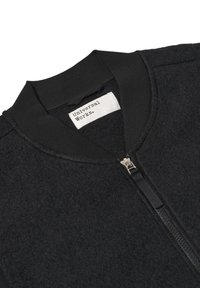 Giubbotto bomber nero con un corpo in lana testurizzata, colletto a coste nero liscio e una zip argentata sul davanti. Etichetta "Universal Works" all'interno.