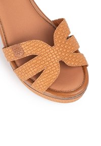 Sandal de cuña en tono marrón claro con un diseño de tira trenzada. Parte superior suave y texturizada con una plantilla acolchada y suela de color marrón claro.