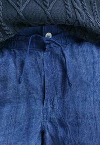 Pantaloni in lino blu navy con vestibilità comoda, dotati di un elastico in vita, lacci regolabili e un semplice dettaglio di chiusura a bottone.