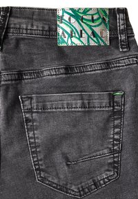 I jeans in denim nero presentano una tasca posteriore con cuciture a contrasto e un accento verde. L'etichetta della vita mostra un design verde e argento.