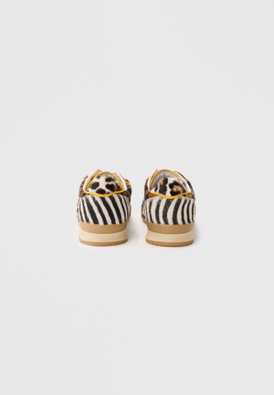 Scarpe con stampa animale caratterizzate da un motivo a strisce di zebra con un accento a stampa leopardata sul retro, realizzate in tessuto texturizzato con una suola color tan.