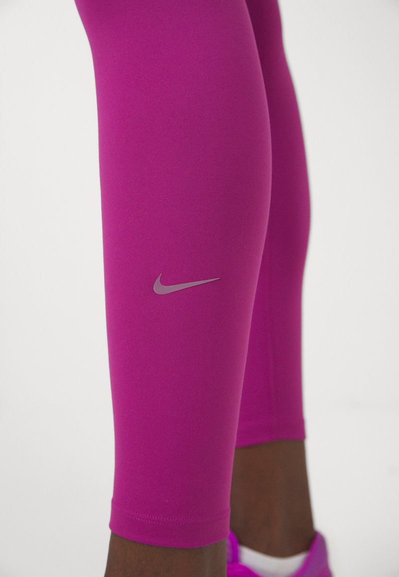 Leggings deportivos fucsias con una textura suave, que presentan un pequeño logo plateado de Nike en la parte inferior de la pierna y un diseño ajustado.