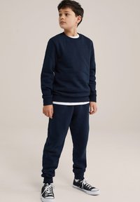 Navy blue sweatshirt and joggers in soft fabric, featuring ribbed cuffs and a relaxed fit, paired with black sneakers.