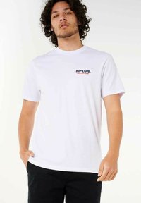 Weißes Baumwoll-T-Shirt mit Rundhalsausschnitt, das ein kleines, farbenfrohes "RIP CURL"-Logo auf der linken Brust zeigt. Kurze Ärmel und lockere Passform.