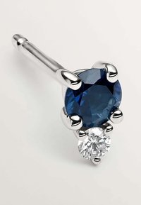 Pendiente de plata con una piedra redonda azul profunda encima de un diamante claro más pequeño, asegurado con cuatro garras, acabado pulido, diseño elegante.