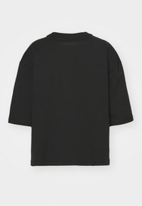 Musta puuvillapaita, jossa on rento leikkaus, lyhyet hihat ja pyöreä kaula-aukko. Selkäpuoli on yksinkertainen ilman muita suunnittelu-elementtejä.