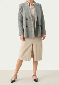 Blazer gris à carreaux croisé avec des boutons noirs, associé à une jupe midi beige côtelée avec une fente à l'avant et des ballerines noires pointues.