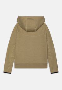 Khaki mikina s kapucí a volným střihem, s švy v kontrastní barvě nitě a černým akcentem na manžetách.