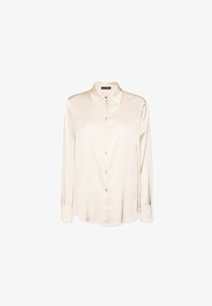 Camicia lunga in seta beige con colletto a punta e chiusura a bottoni, caratterizzata da una texture liscia e un orlo curvato per un fit rilassato.