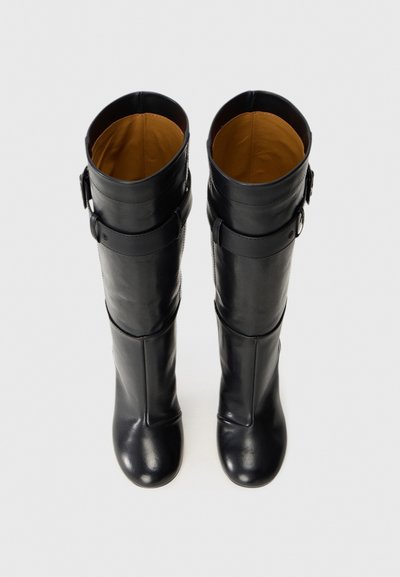 Pair of black leather knee-high boots with buckled straps near the top, viewed from above, against a white background.
