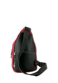 Sac en bandoulière composé d'un tissu perforé noir avec des accents rouges, doté d'une poche zippée et d'une bandoulière réglable pour un transport facile.