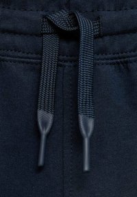 Mörkblå sweatpants med en tjock, elastisk midja som har en texturerad dragsko. Ändarna på dragskon är täckta med ett mörkt material.