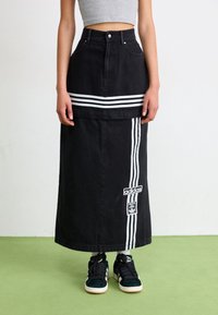 Svart denimmaxikjol med vita Adidas-ränder och logopatch; åtsittande midja, utsvängd form, knäppning fram och sidofickor.