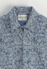 Veste zippée à motif floral bleu avec un col rabattu, offrant une texture douce et une étiquette de marque à l'intérieur. Taille 5.