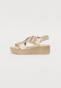 Metallic gold wedge sandals with cross-strap design, adjustable buckle, and woven texture on the platform for added grip.
