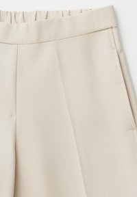 Beige broek met hoge taille en een gladde textuur, elastische tailleband, zijzakken en subtiele stiksel details.