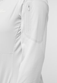Witte midlayer jacket met een gladde textuur, slim fit en een ritszak op de bovenarm. Minimalistisch ontwerp met subtiele branding.