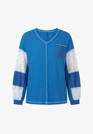 Niebieska koszula z długim rękawem, dekoltem w serek, przednią kieszenią oraz białymi koronkowymi panelami na rękawach, które na przemian występują z jednolitym niebieskim materiałem.