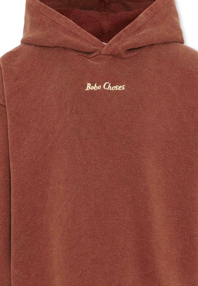 Sweat à capuche marron rouille avec un court texte brodé « Bobo Choses » centré sur la poitrine.