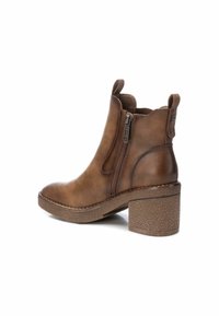 Botas de tobillo de cuero marrón con un talón de bloque texturizado, cremallera lateral y tiradores. Tienen una puntera redondeada y un forro interior similar al ante.