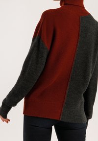 Strickpullover mit hohem Kragen in Rost- und Anthrazitfarben, aus einem strukturierten Stoff mit kontrastierenden Paneeldesign.