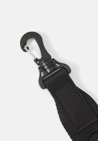 Svart nylonreim med en plastkrok. Har en teksturert overflate og en metallklemme. Solid design for sikker festing.