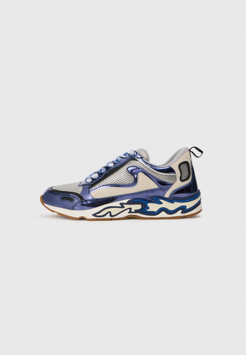Sportliche Sneakers mit einem metallischen navy und silbernen Mesh-Obermaterial, übertrieben gewellter weißer und blauer Sohle sowie blauen Schnürsenkeln. Mit einer Zuglasche hinten.
