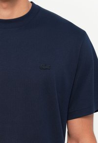 Navyblauwe katoenen t-shirt met ronde hals, korte mouwen en geborduurd logo op de borst. Soepele textuur en eenvoudig ontwerp.