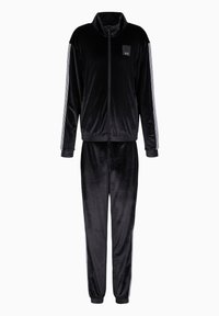 Tuta in velluto nero con colletto alto e frontale con zip. I pantaloni presentano polsini elasticizzati e strisce laterali. Piccolo logo nella zona del petto della giacca.