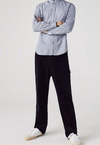 Vaaleansininen ruudullinen paita nappikauluksella, yhdistetty tummiin samettihousuihin ja valkoisiin lenkkareihin. Yksinkertainen, rento asu.