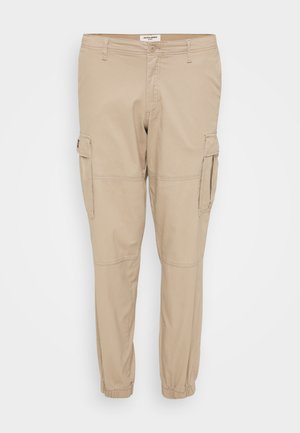 Beige cargo pants made of lightweight fabric, featuring tapered legs, elastic cuffs, and side pockets with flap closures for utility.