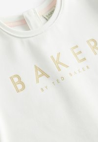Weißes Baumwollhemd mit goldgeprägtem Text "BAKER BY TED BAKER", Rundhalsausschnitt und einem Schlitz für ein einfaches Ankleiden.