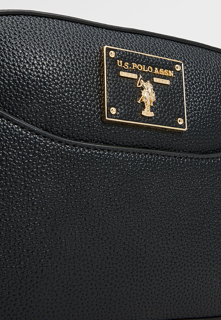 Sac noir texturé avec un logo équestre en métal doré. Bords lisses et forme structurée.