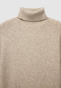 Pull en col roulé beige en matériau tricoté doux, présentant un col roulé et un motif légèrement texturé sur l'ensemble.