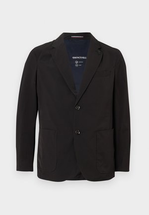 Veste noire compressible en tissu lisse et léger. Elle possède un col à revers, deux poches avant et deux boutons. L'intérieur affiche la marque.