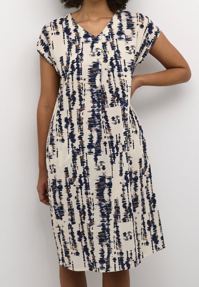 Robe à col en V et manches courtes, couleur crème, avec des motifs de coups de pinceau verticaux en bleu, marron et crème ; coupe ample et longueur jusqu'au genou.