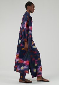 Lang, vloeiende blouse en bijpassende broek in een meerkleurig abstract patroon met marineblauw, rood, geel en paarse tinten. Glad materiaal, comfortabele pasvorm.