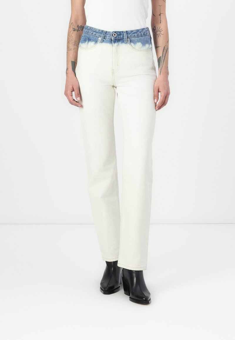 Jeans de cintura alta com um cós de denim azul desbotado e pernas de um bege claro, apresentando um corte reto e detalhes de costura mínimos.
