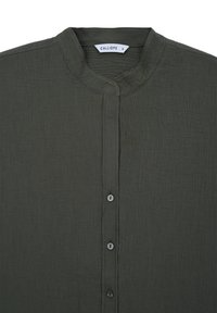 Camicia verde oliva, texture, con colletto alla mandarina. Presenta una chiusura frontale con bottoni piccoli. Le etichette indicano "CALLIOPE" e taglia "S."