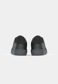 Black sneakers with a smooth leather upper, featuring a cushioned back, gray rubber sole, and embossed CLAE logo on the heel.