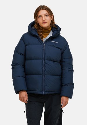 Giacca puffa blu navy con chiusura a zip, ampio cappuccio e design trapuntato. Presenta un logo sul lato sinistro del petto e polsini a costine.