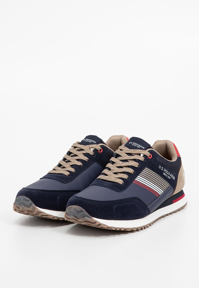 Baskets marine en daim bleu foncé et beige, dotées d'une semelle en caoutchouc texturée, de lacets beige et d'accents de rayures rouges sur le côté.
