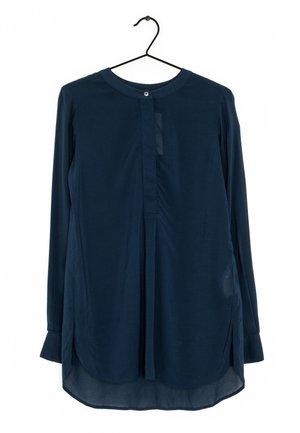 Langermige marineblauwe blouse met een ronde hals en een enkele knoop aan de voorkant, hangend aan een zwarte hanger tegen een witte achtergrond.