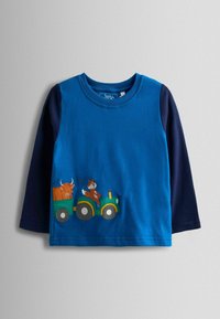 Zils garu piedurkņu mazuļu krekls ar tumši ziliem piedurknēm un grafiku, kurā attēlots traktors, kas velk piekabi ar bulli, ko vada lapsa.
