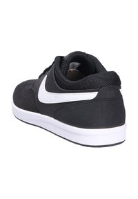 Black sneakers with a suede and mesh upper, featuring a white Nike swoosh. Low profile with a padded collar and white rubber sole.