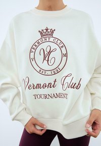 Felpa crema con logo stampato marrone che presenta una corona e la scritta "Vermont Club Tournament" in caratteri corsivi e in serif; vestibilità rilassata.