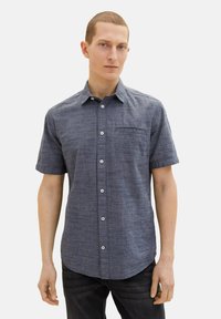 Kortärmad skjorta i strukturerad mörkblå tyg, med knäppning framtill, bröstficka och vita knappar.
