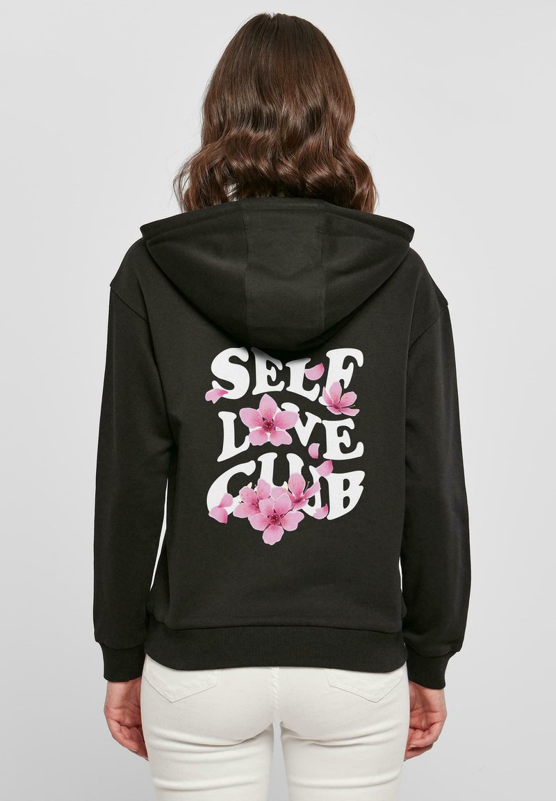 Felpa nera con una grande grafica bianca con la scritta "SELF LOVE CLUB", arricchita da illustrazioni floreali rosa. Miscela di cotone, vestibilità rilassata, tasche anteriori.