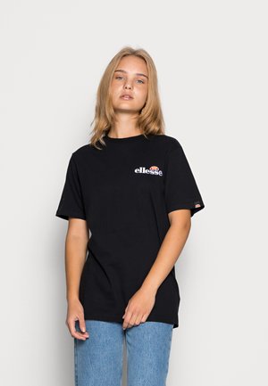 Schwarzes Baumwoll-T-Shirt mit kurzen Ärmeln, das ein weißes "ellesse"-Logo und ein rot-weißes Grafikdesign zeigt. Kombiniert mit hellblauen Jeans.